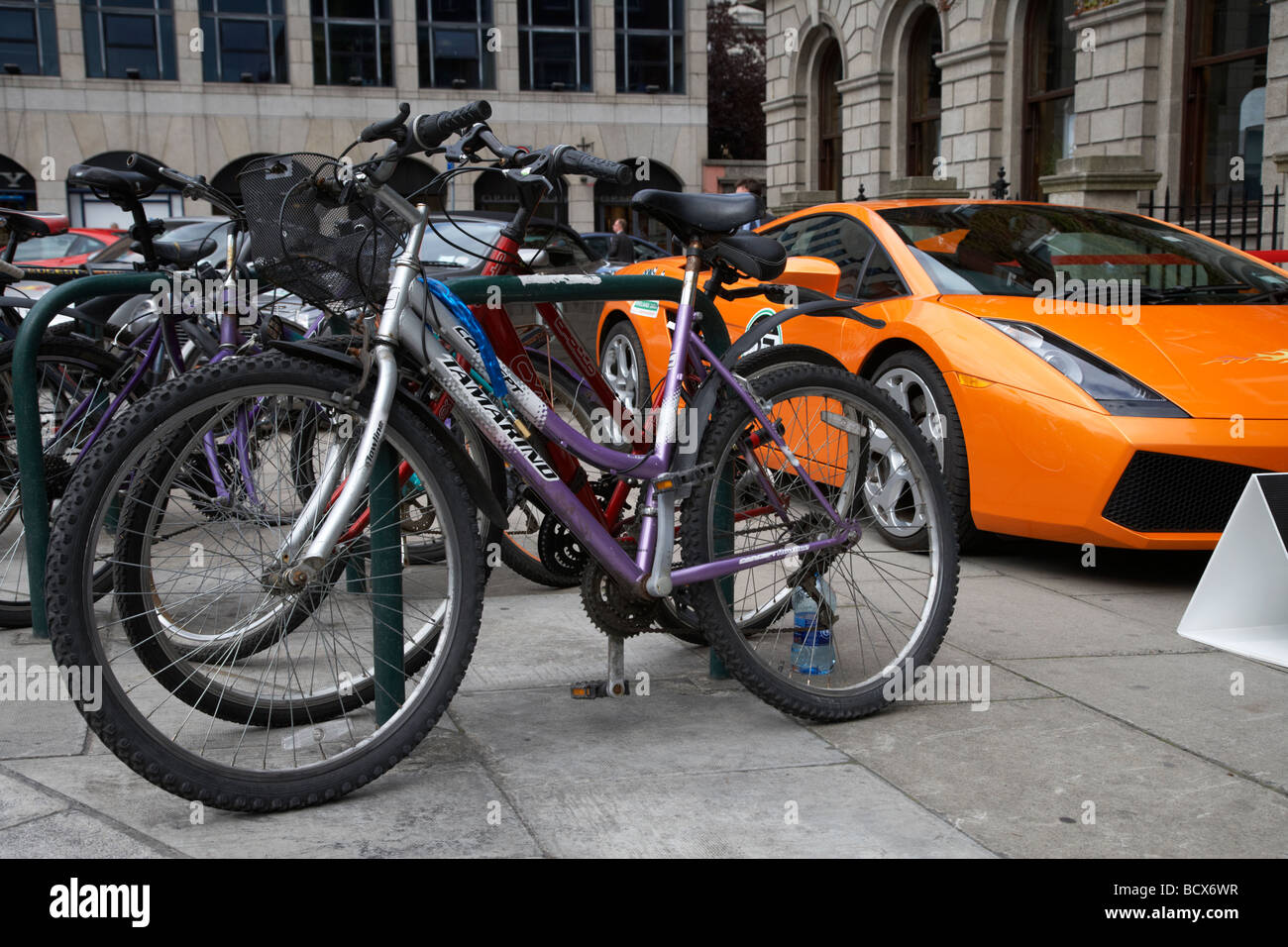 Lamborghini Sportwagen auf Bürgersteig neben Zeile der Fahrräder geparkt Dublin Republik von Irland, die Kluft zwischen Arm und Reich und soziale Ungleichheit Stockfoto