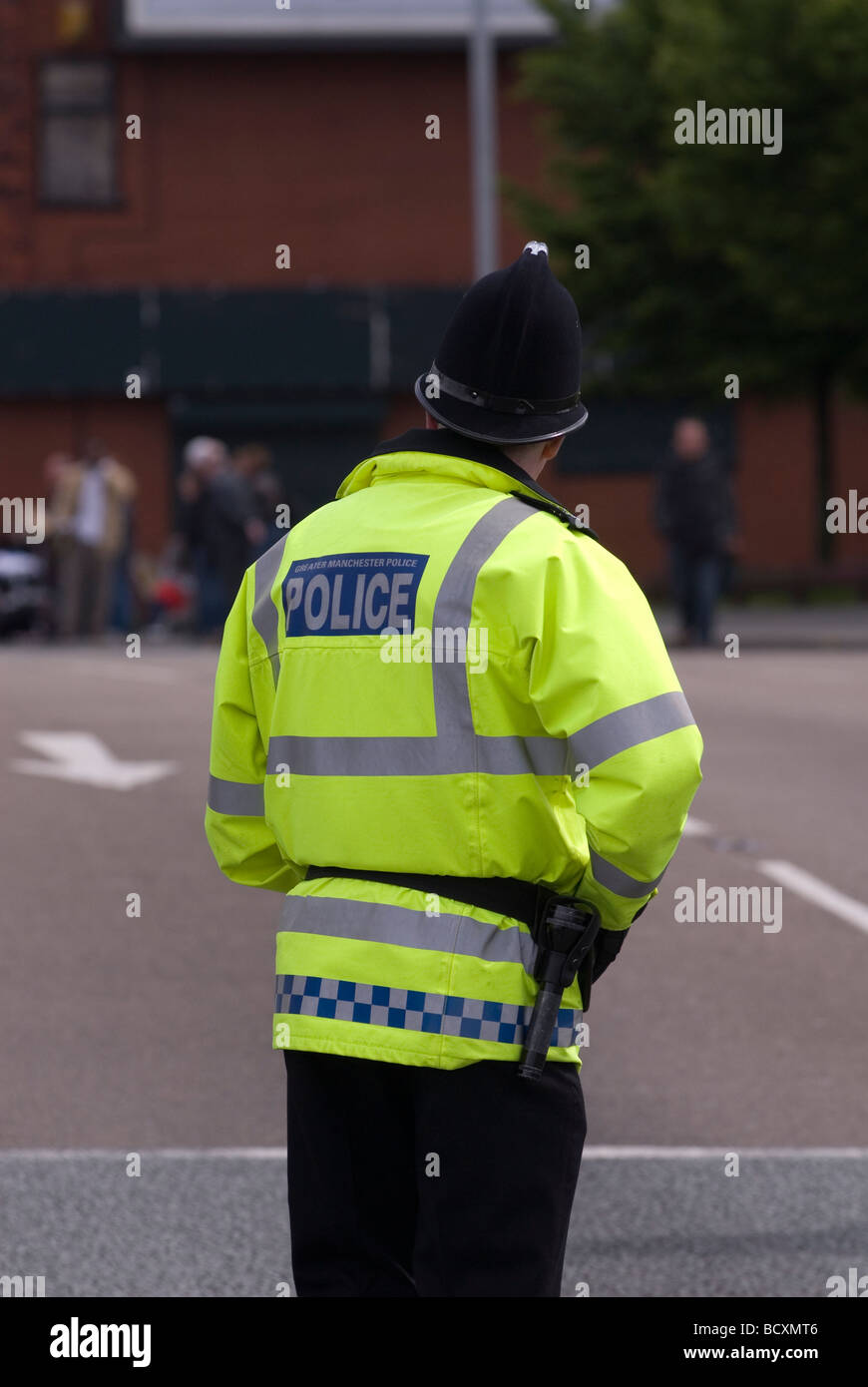 Polizisten stehen auf der Straße beobachten eine Menschenmenge in der Ferne Manchester UK Stockfoto