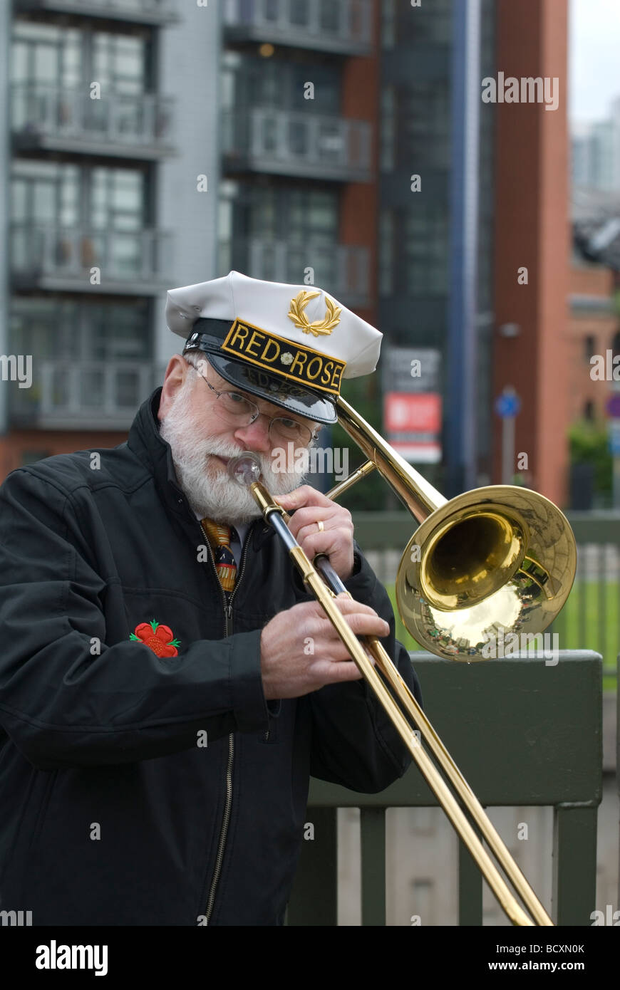 Rote rose Bandmitglied spielt die Posaune im Freien in Manchester UK Stockfoto