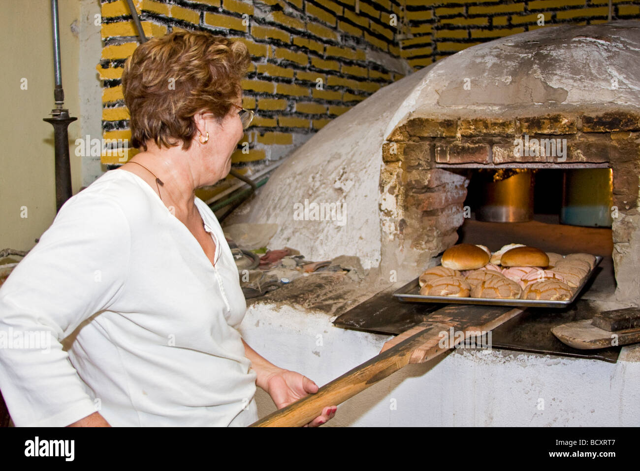 Frau legt Brot im traditionellen Lehmofen zum Brotbacken in El Quelite, Mexiko Stockfoto