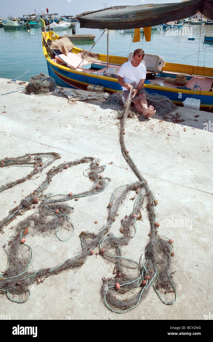 Ein Fischer in Marsaxlokk, Malta, arbeitet mit seinen Netzen in der Nachmittagssonne, Marsaxlokk, Malta Stockfoto
