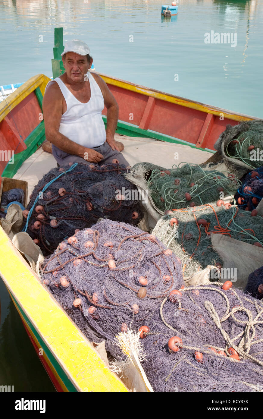 Ein Fischer in Marsaxlokk, Malta, arbeitet mit seinen Netzen in der Nachmittagssonne, Marsaxlokk, Malta Stockfoto