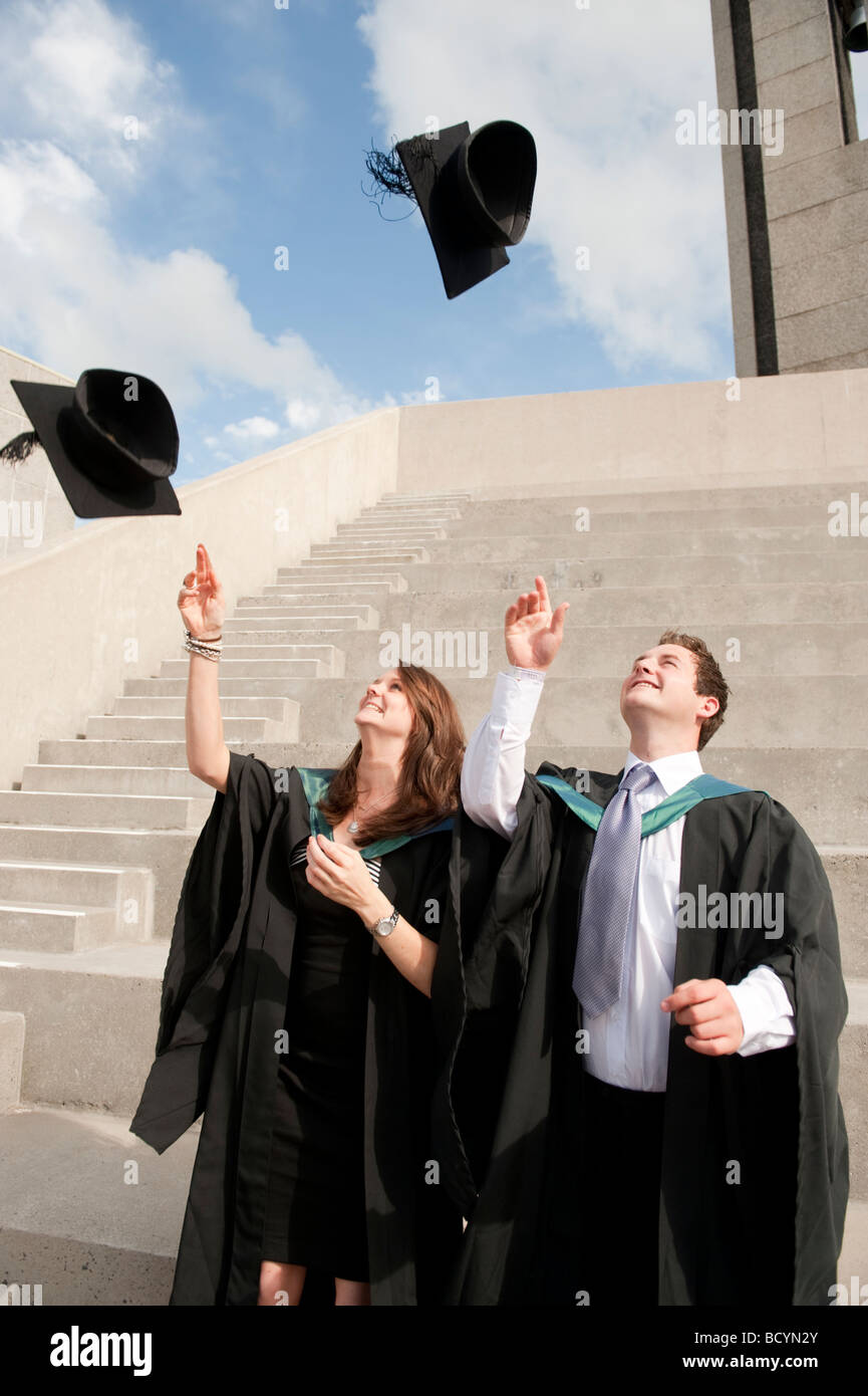 Zwei 2 Aberystwyth University Studenten Abschlusstag werfen ihre Mützen in die Luft in der Feier Wales UK Stockfoto
