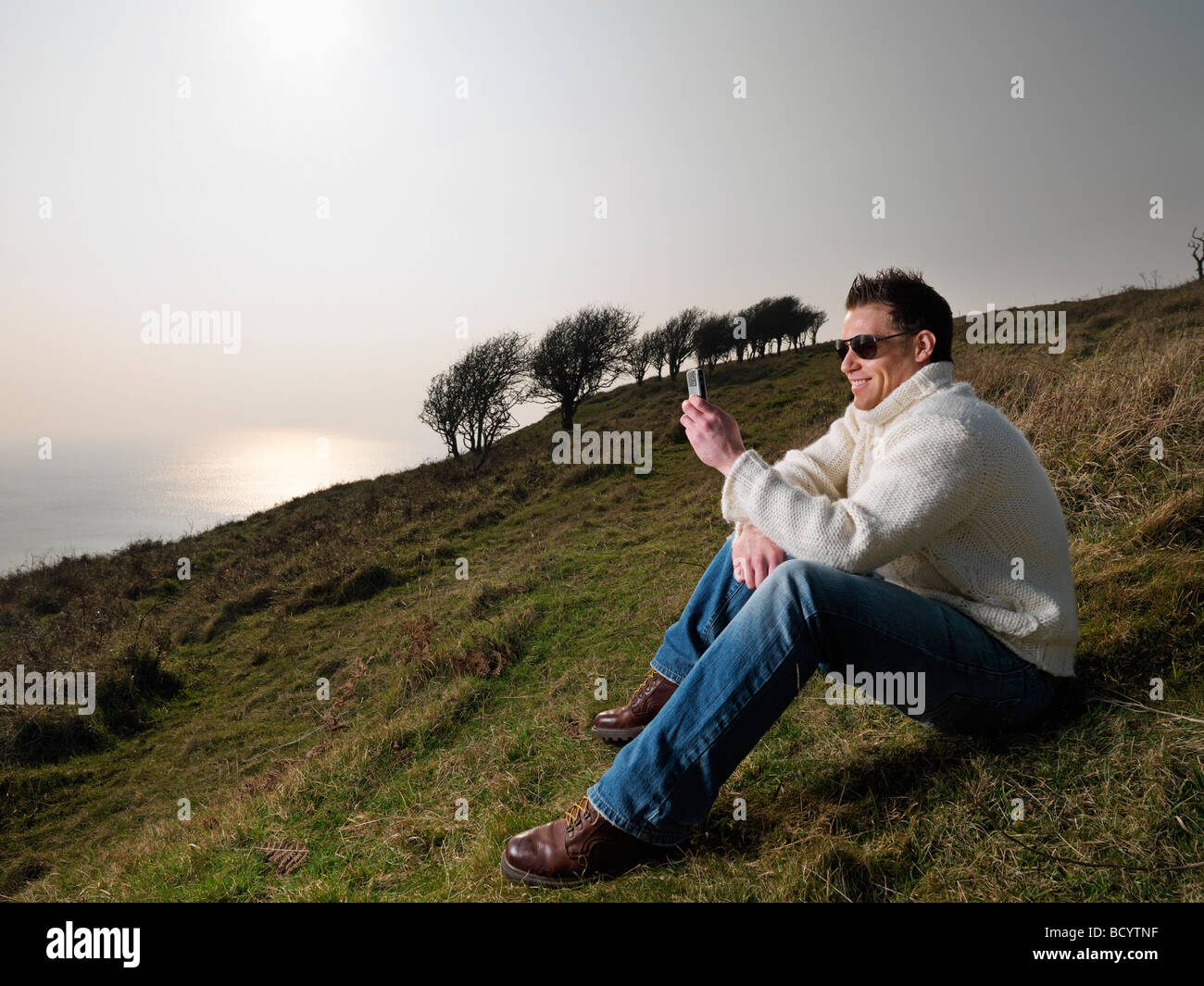 Mann am Telefon auf küstennahen Hügel Stockfoto