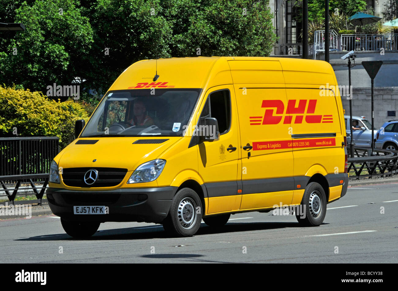 Nahaufnahme der Vorderansicht der Marke Mercedes gelbes DHL Logo auf Paketzustellwagen und Fahrer, der entlang der Park Lane Mayfair London England fährt Stockfoto