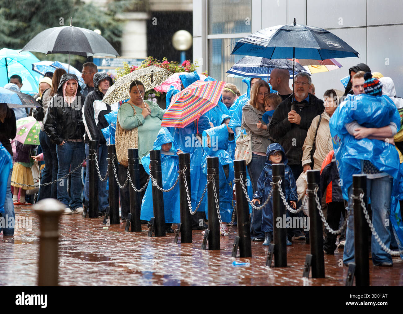 Besucher das Sealife Centre in Birmingham, UK, in die Warteschlange draußen im Regen. Stockfoto