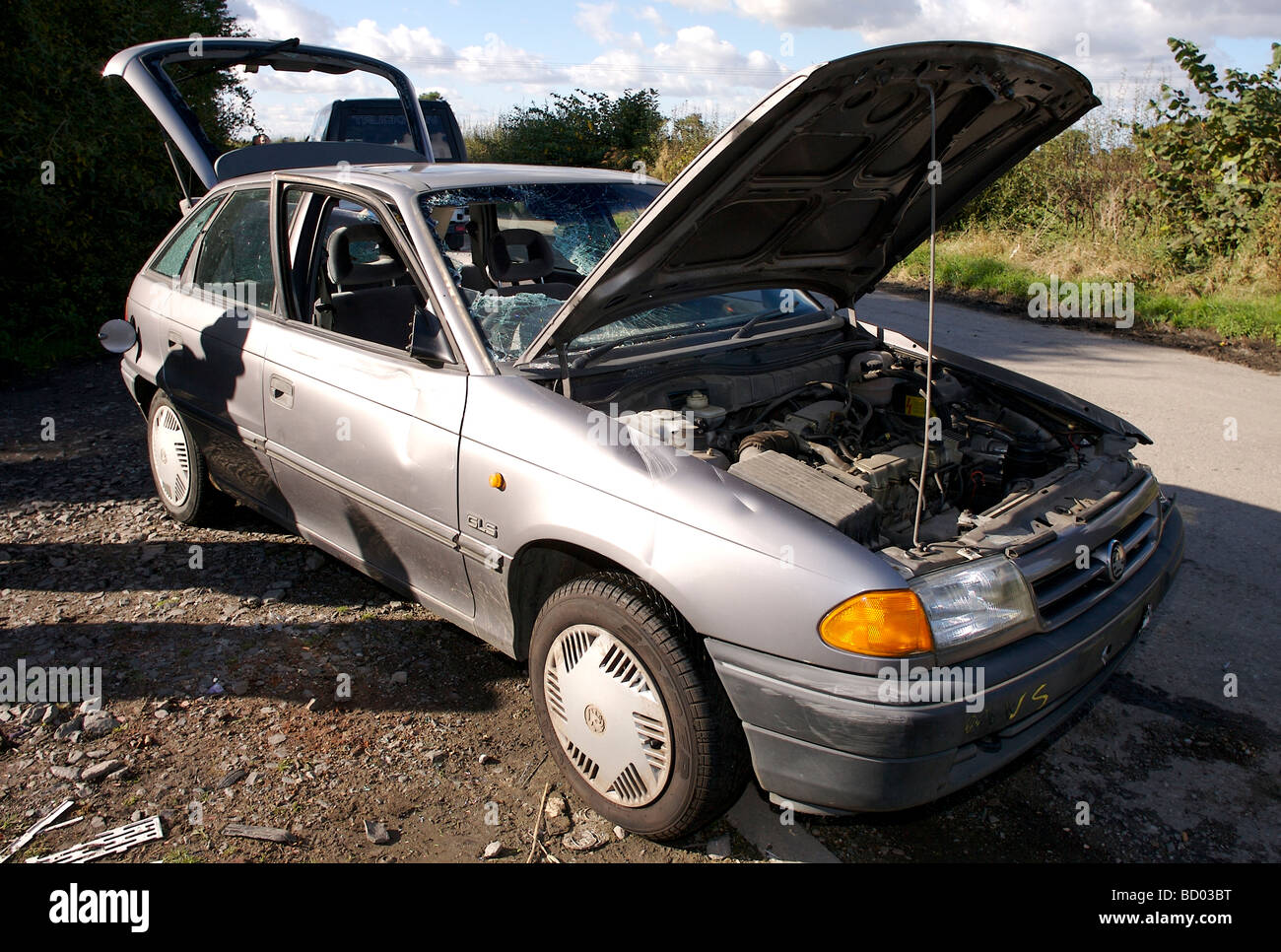Ein gestohlenes Vauxhall Astra Auto auf einer Landstrasse mit Windows aufgegeben zerschlagen und Motorhaube geöffnet. Stockfoto