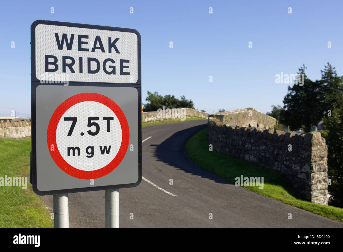 schwach zu überbrücken, 7 5 Tonnen Mgw Gewicht Einschränkung Straßenschild und Straße führt über die alte Steinbrücke Stockfoto