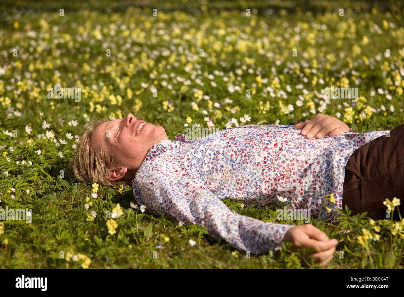 Mann liegt im Rasen mit Frühlingsblumen Stockfoto