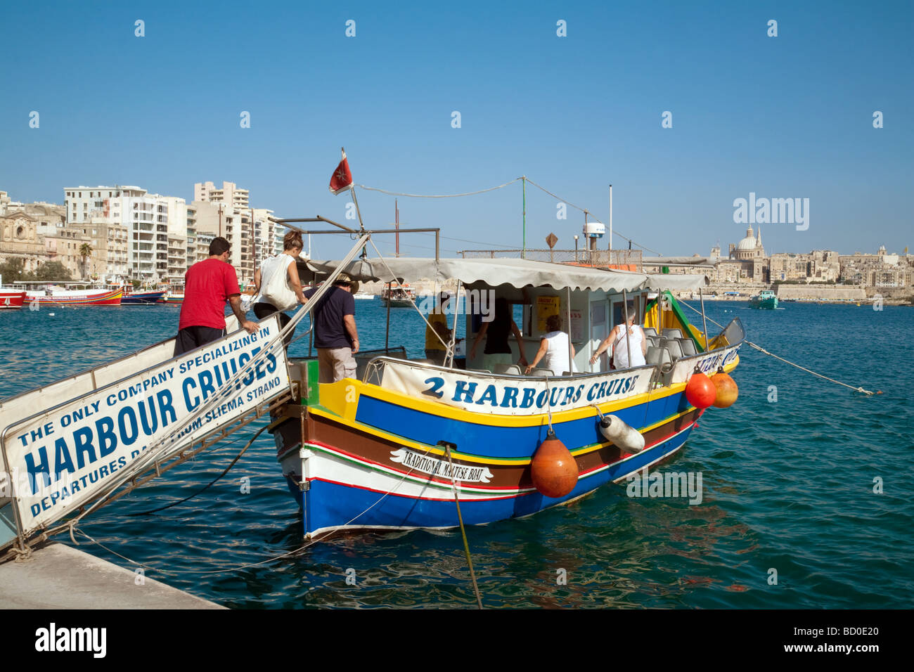 Touristen einsteigen in eine Luzzu (traditionelle maltesische Boot) für eine Kreuzfahrt rund um den Hafen von Sliema, Valletta, Malta Stockfoto