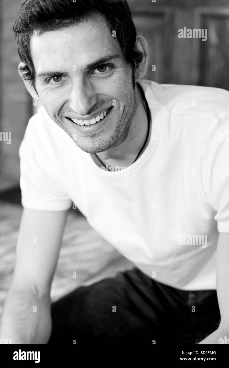 Engen Schuss von männlichen lächelnd und sitzt lässig, mit Ellenbogen am Knie nach vorne lehnen. Schwarz und weiß. Toronto, Ontario. Stockfoto