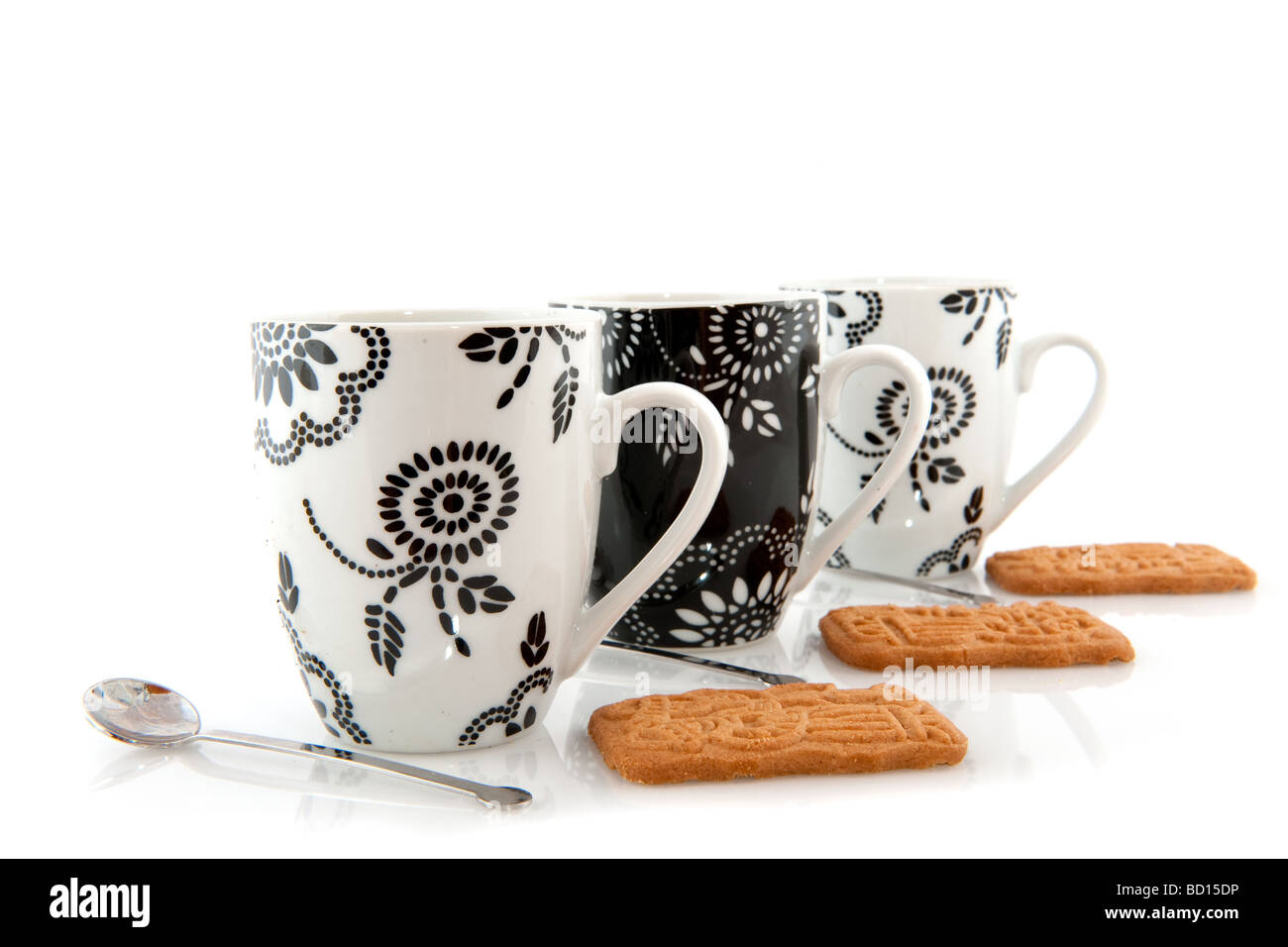 schwarze und weiße Kaffeebecher mit Keksen und Löffel Stockfoto