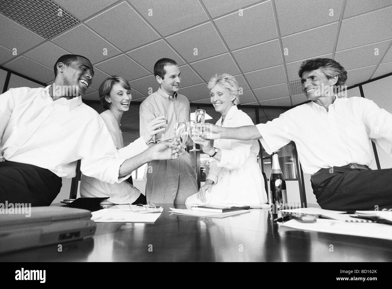 Geschäftspartnern klirrende Gläser, feiert mit Champagner im Büro Stockfoto