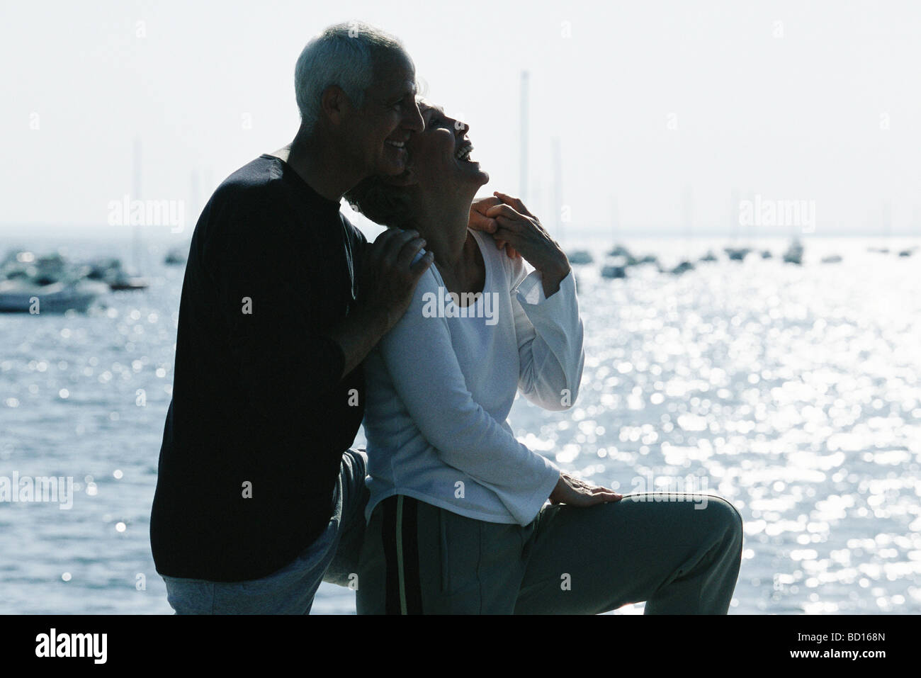 Älteres paar lachen zusammen, Meer im Hintergrund Stockfoto
