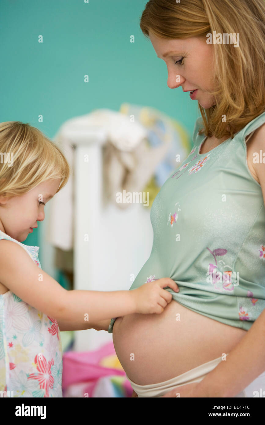 Kleines Mädchen Blick auf Mutters Bauch Stockfoto