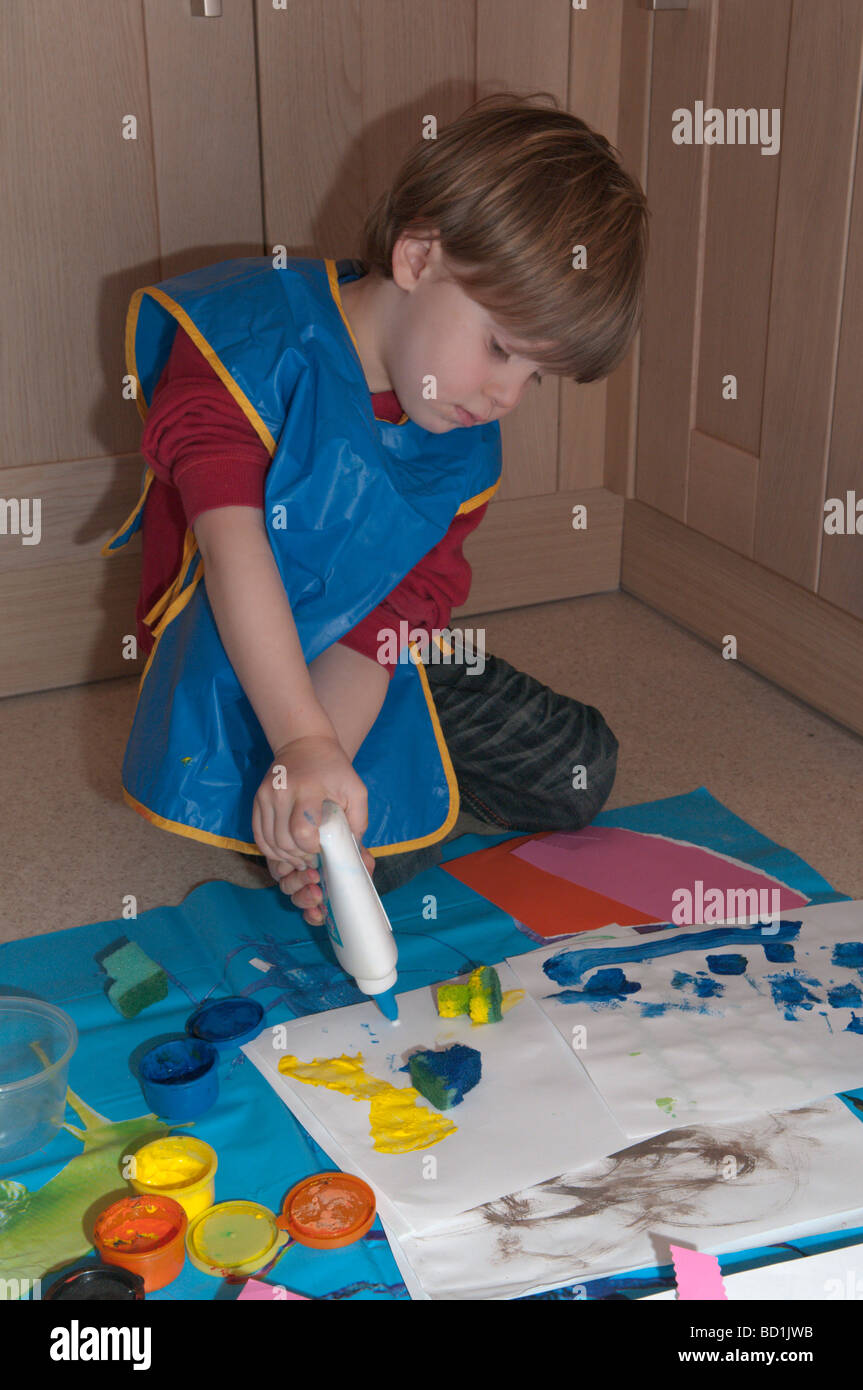 Kleiner Junge auf Küchenboden, der mit Pinseln, Schwämmen und Leimarbeiten spielt, kreativer Künstler, 3 Jahre alt Stockfoto