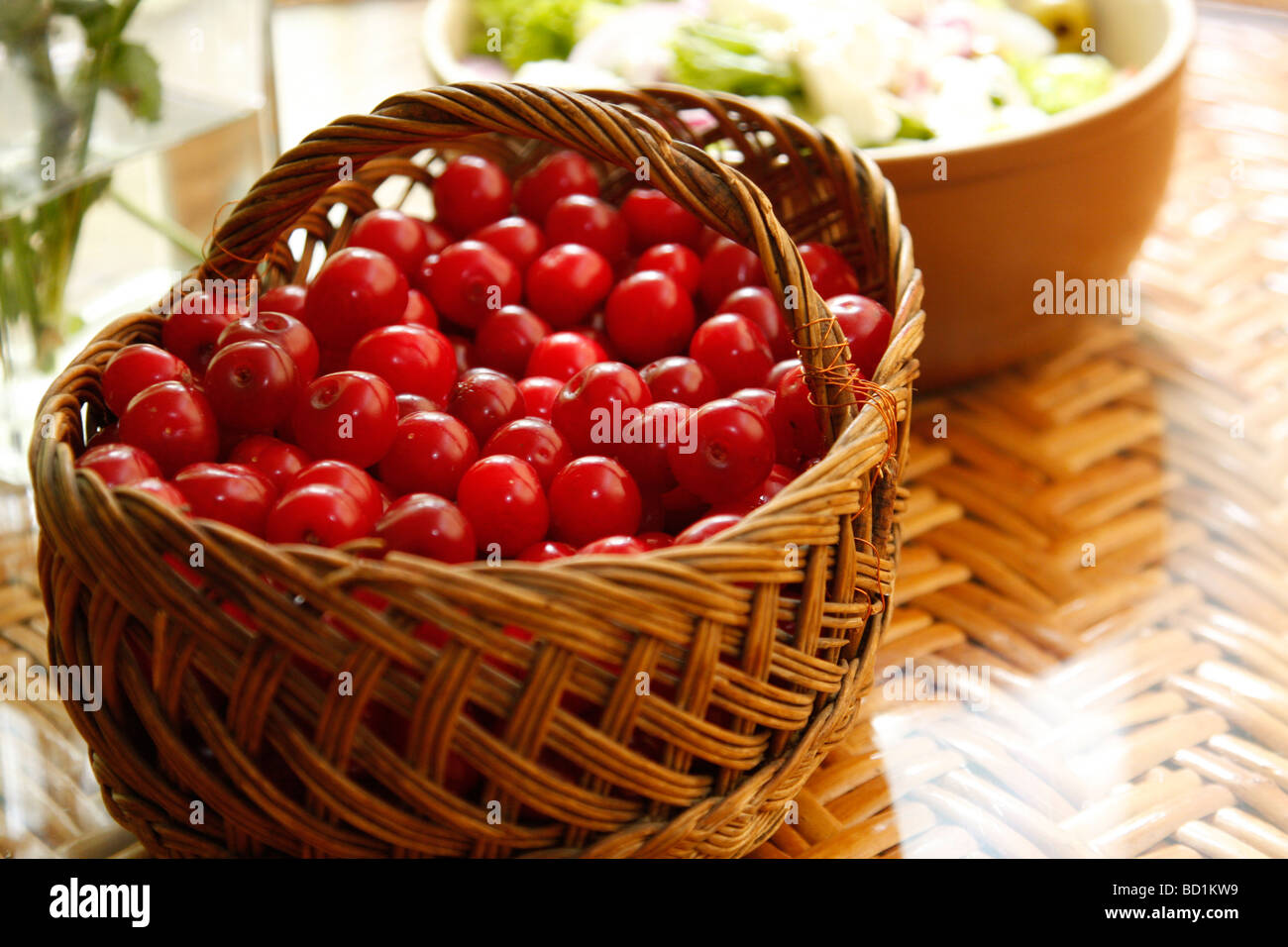 Frische Kirschen in einem Korb auf der Tischplatte mit einigen anderen frischen grünen Essen Stockfoto