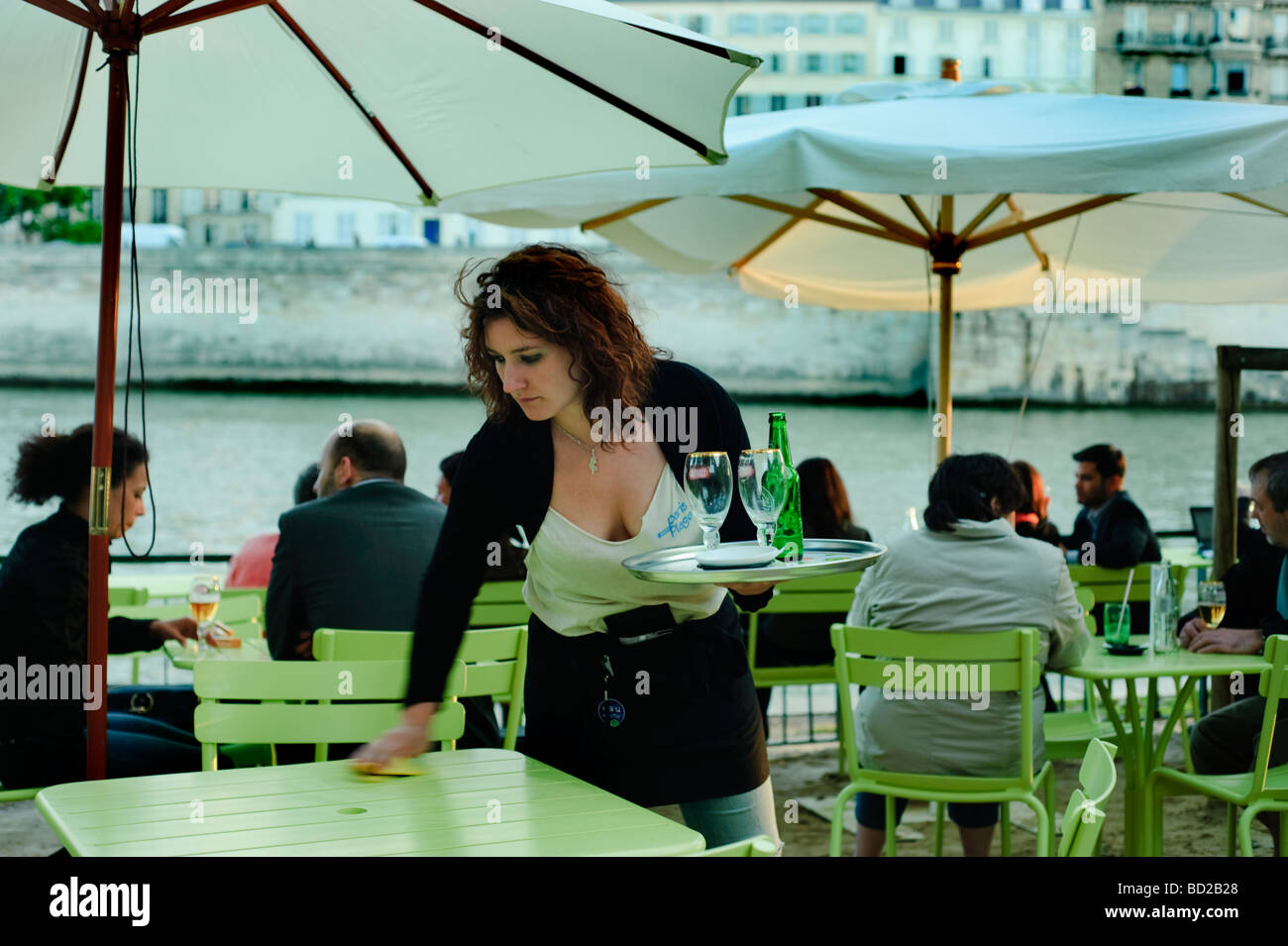 Paris Frankreich, junge Frau, Kellnerin, Reinigungstische im „French Bistro Restaurant“ am Quay „seine River“ an den „Paris Plages“-Schirmen Stockfoto