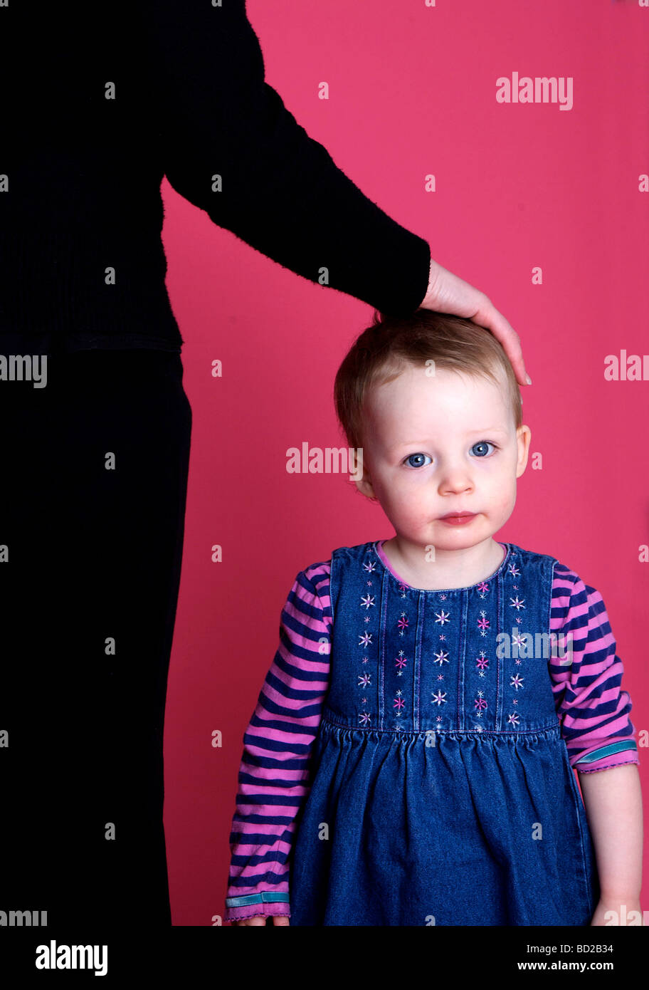 Kleinkind mit Erwachsenen Hand am Kopf Stockfoto