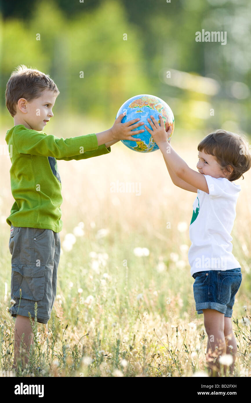 Kinder spielen mit Globus auf Wiese Stockfoto