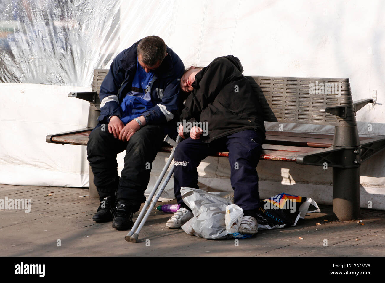 Zwei Männer schlafen auf einer Stadt-Zentrum-Bank im Vereinigten Königreich Stockfoto