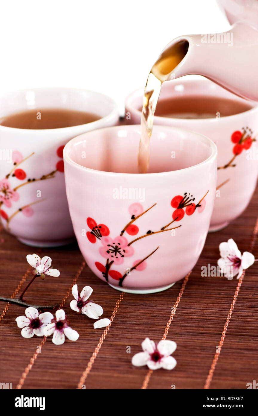 Grüner Tee in Tassen mit Kirschblüten Design gießen Stockfoto