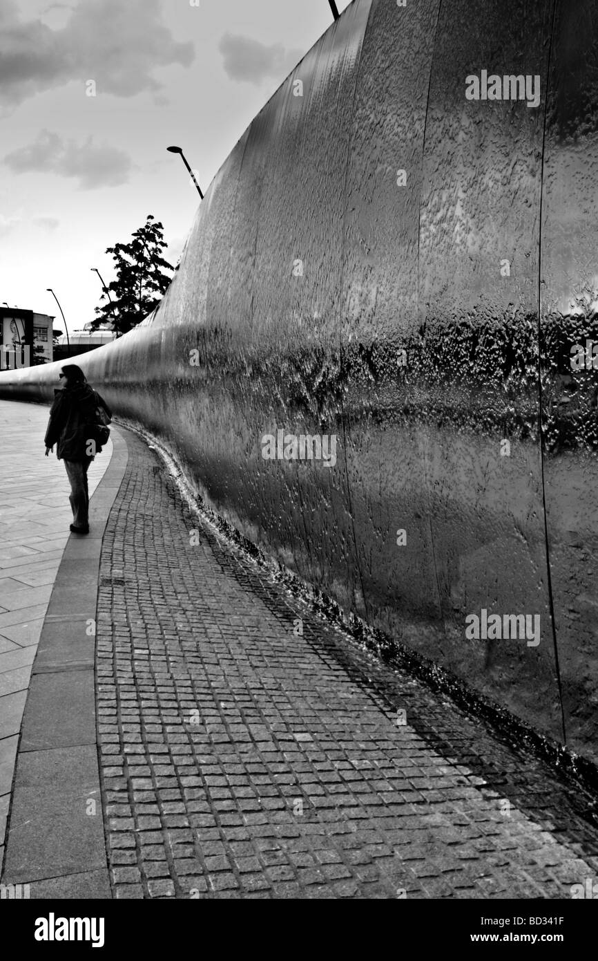 Eine junge Frau zu Fuß neben der Wasserkaskade in Garbe Platz vor dem Bahnhof in Sheffield. Stockfoto