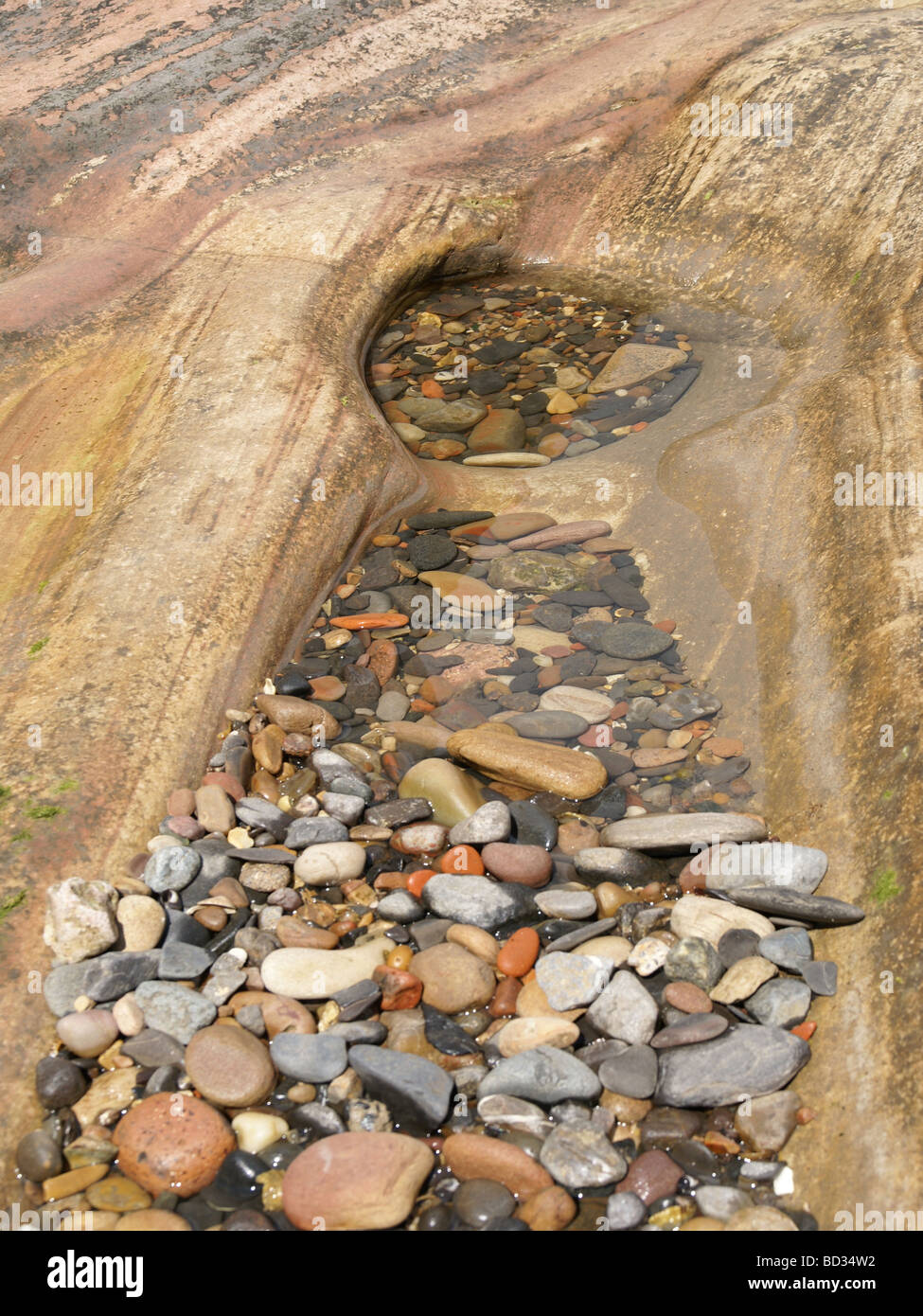 Buntes Wasser getragen Steinen Pebbels im Felsenbad bei Ebbe gefangen genommen Stockfoto