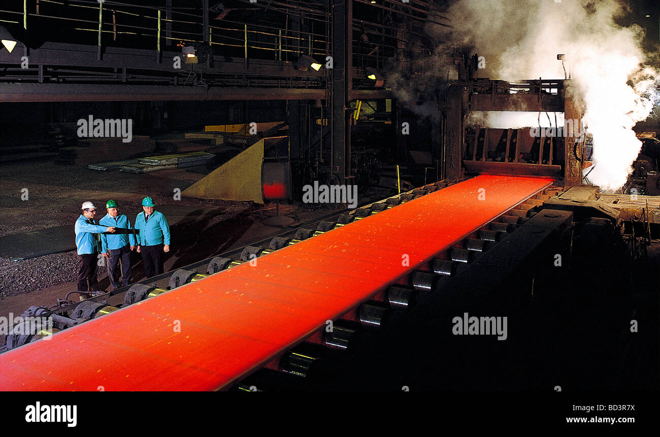 Drei Führungskräfte sehen den Walzprozess des flüssigen Stahls in einer Pennsylvania Stahl-Mühle Stockfoto