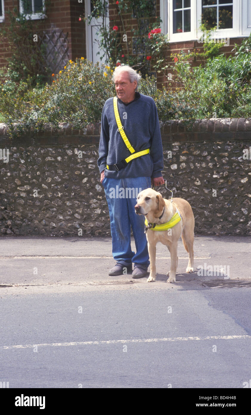 blinder Mann stand an der Seite der Straße mit seinem Blindenhund Stockfoto