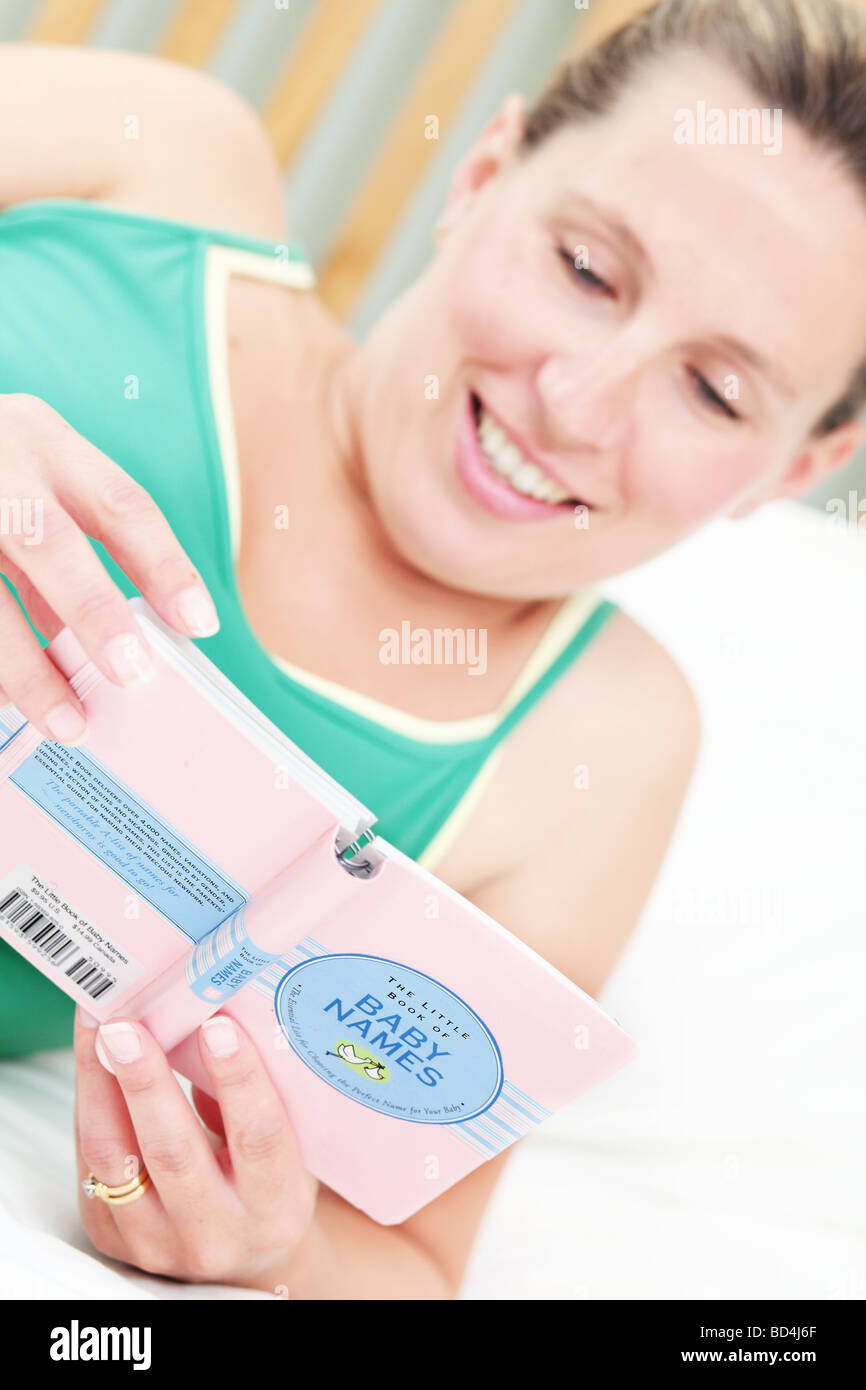 Eine schwangere Frau lag auf ihrem Bett ein Babys Namen Buch zu lesen. Stockfoto