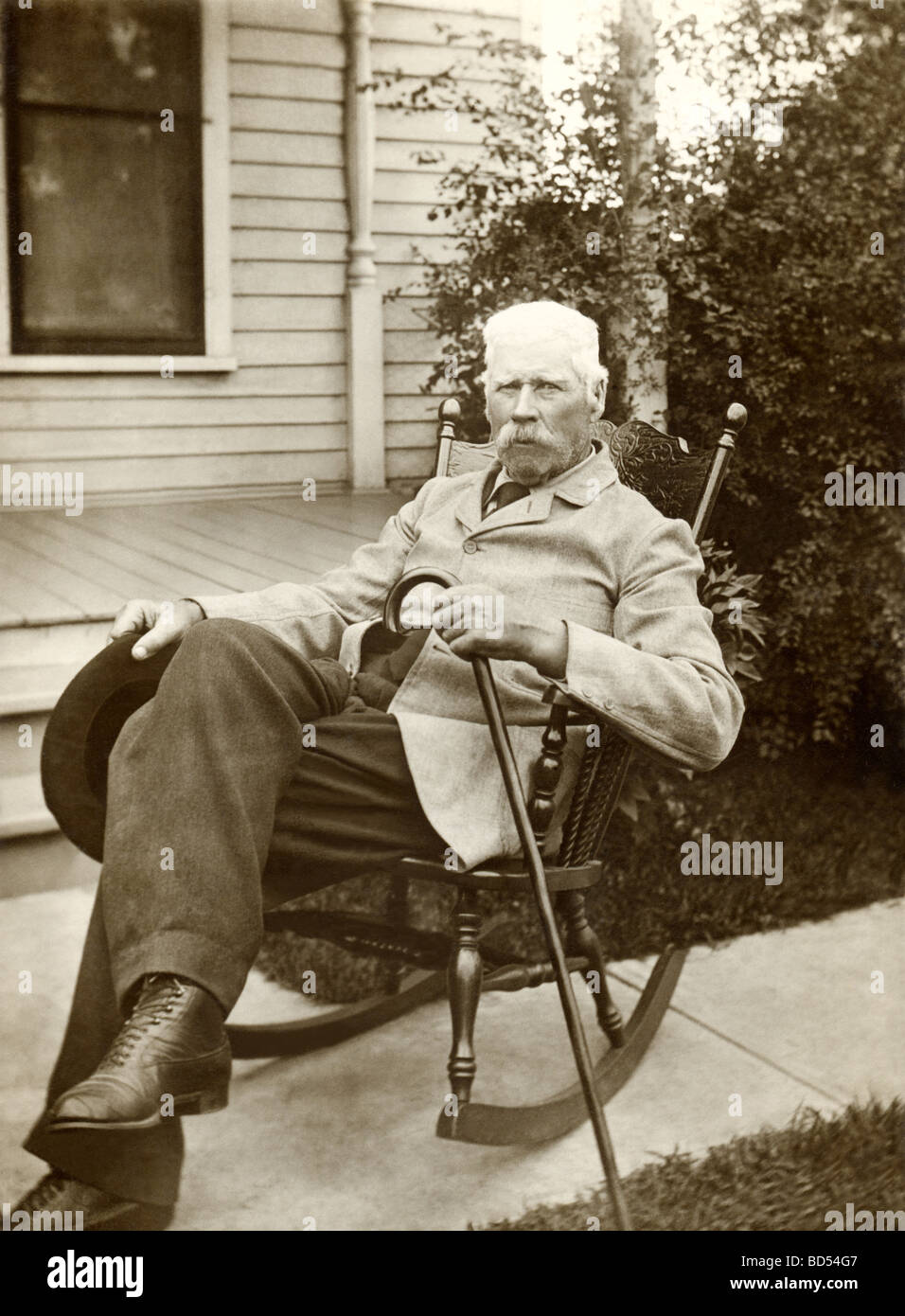 Heck Greis im Schaukelstuhl auf Bürgersteig Stockfoto