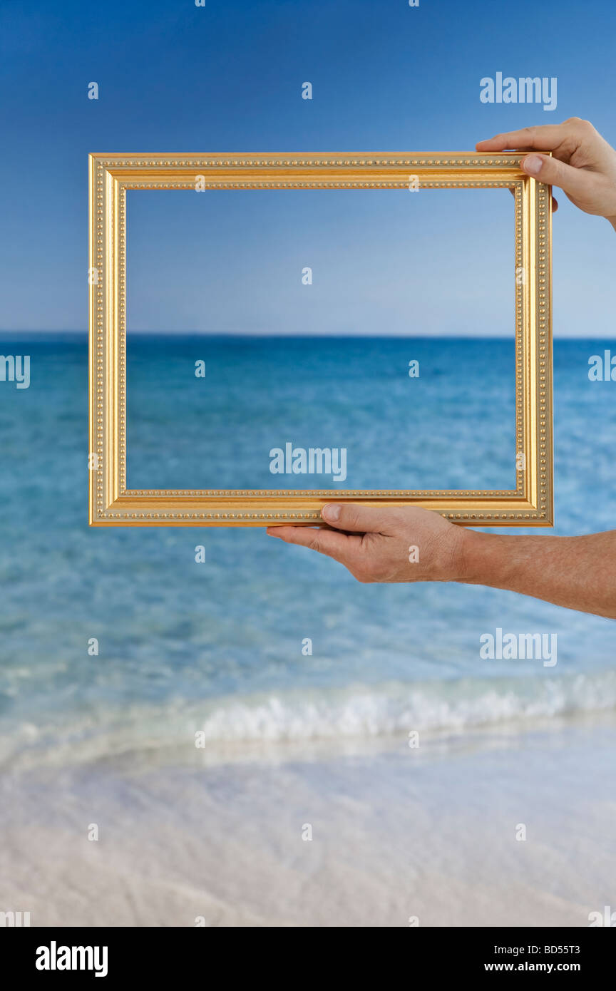 Hände halten einen Bilderrahmen an einem Strand Stockfoto