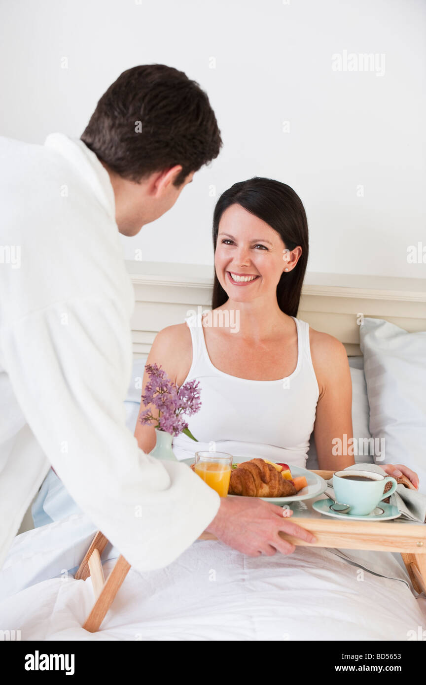 Ein Mann, eine Frau-Frühstück im Bett zu bringen Stockfoto