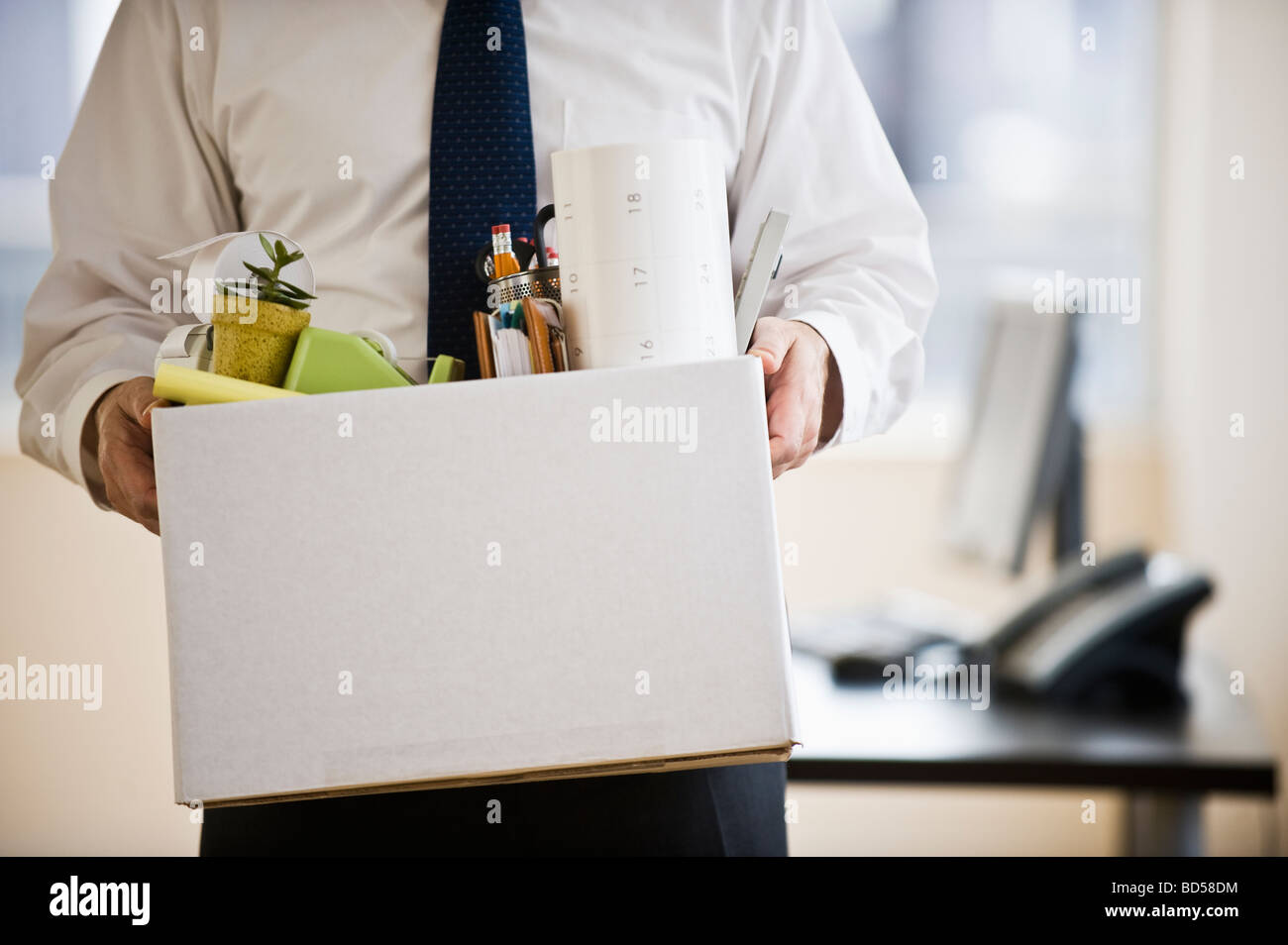 Ein Geschäftsmann mit einer Kiste voller Schreibtisch Zeug Stockfoto