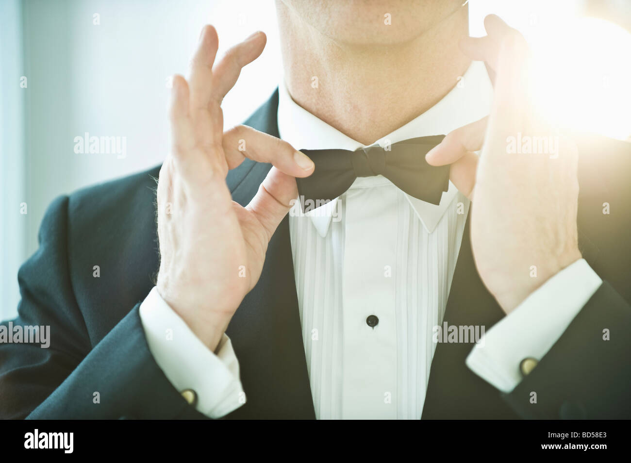 Ein Mann in einen Smoking Festsetzung seiner Fliege Stockfoto