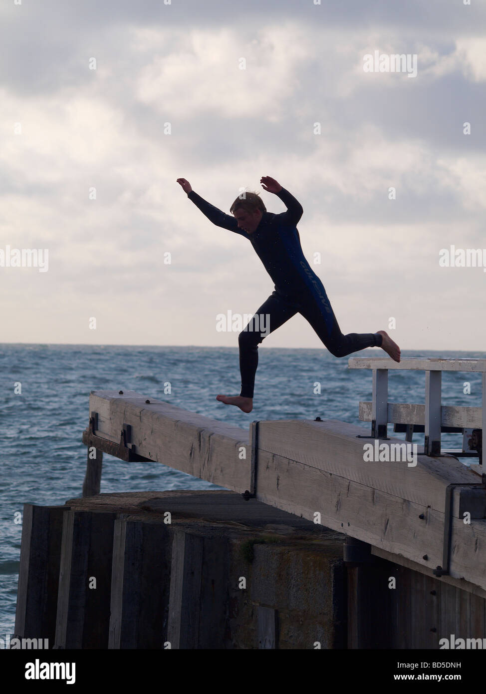 Silhouette eines Teenagers Sprung von der Schleuse in das Meer, Bude, Cornwall Stockfoto