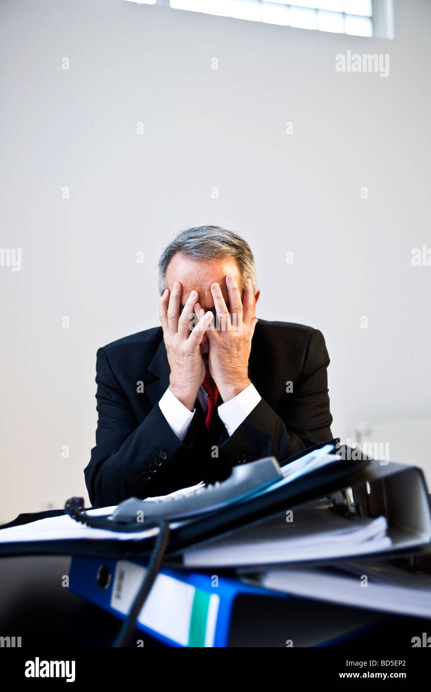 Verzweifelte Manager vor einem Berg von Ordnern Stockfoto