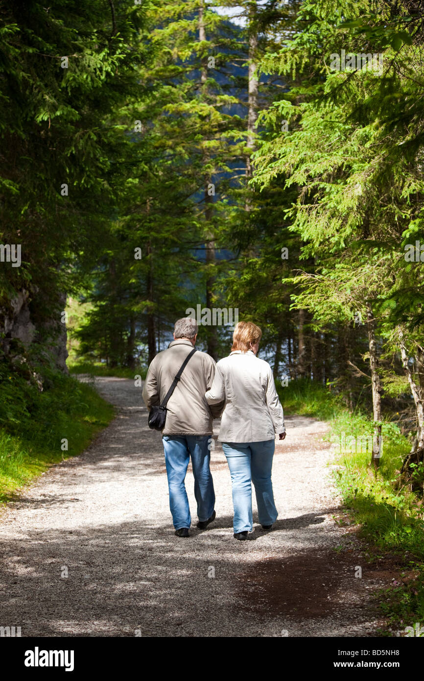 Paare, die über einen Waldweg durch die Bäume Stockfoto