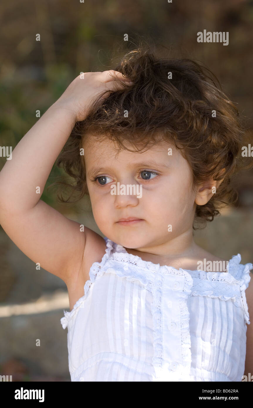 Kleines Mädchen mit der Hand über dem Kopf im freien Stockfoto