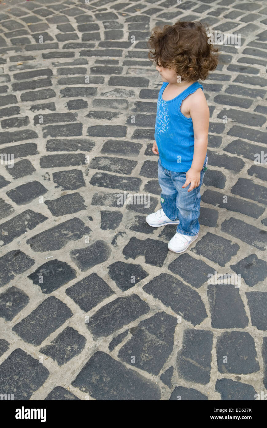 Junge Mädchen stehen auf einer gepflasterten Straße Stockfoto