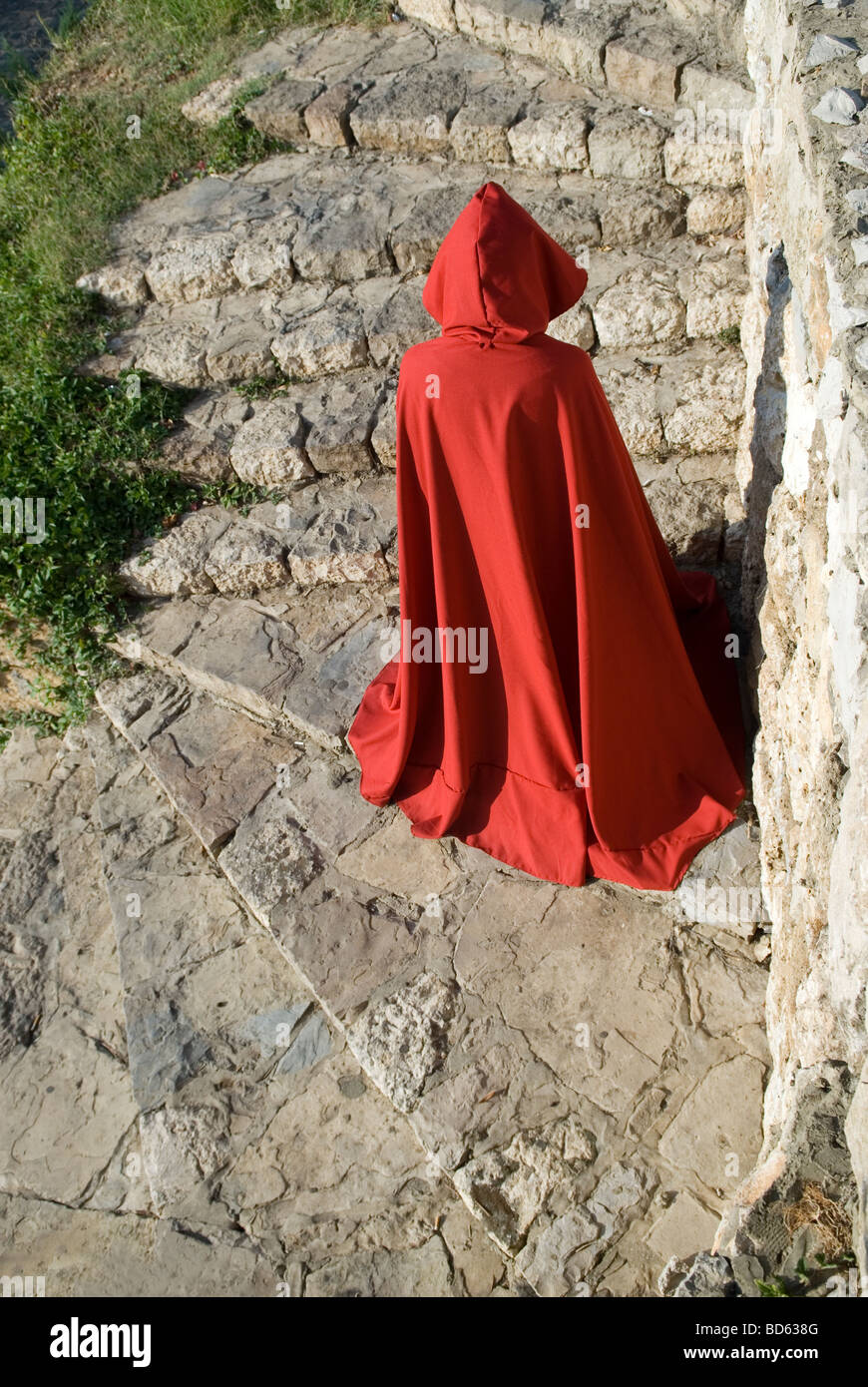 Geheimnisvolle Figur im roten Mantel, steinerne Treppe hinunter Klettern Stockfoto