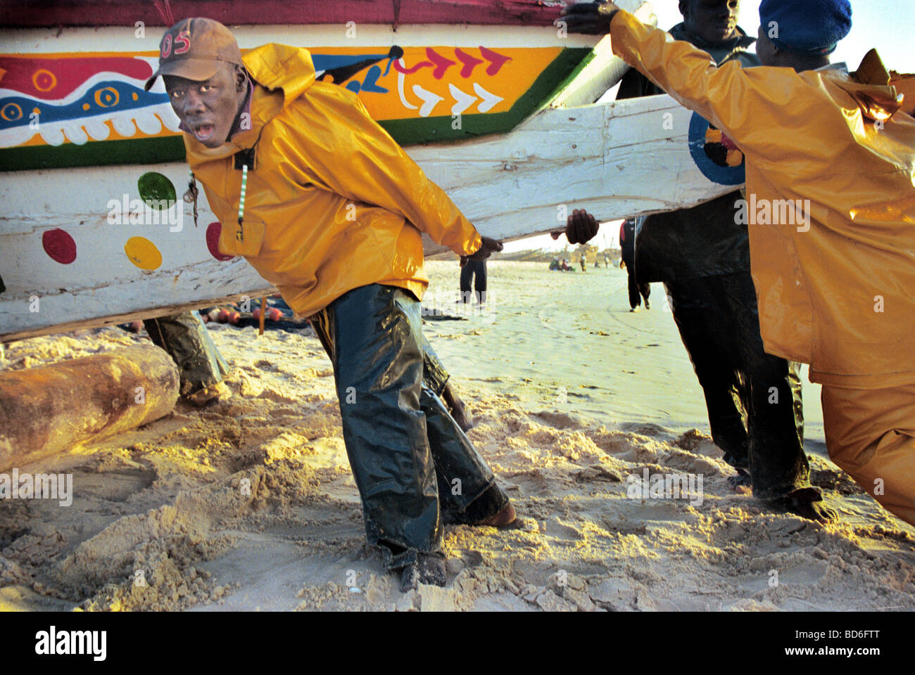 Menschen helfen, ein Boot ans Ufer in Westafrika zu schieben. (Foto von Ami Vitale) Stockfoto