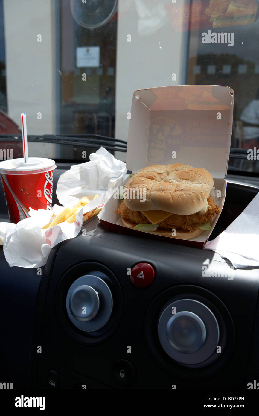 KFC Burger Pommes und Cola auf dem Armaturenbrett eines Autos van dem schnellen Fastfood Mittagessen Stockfoto