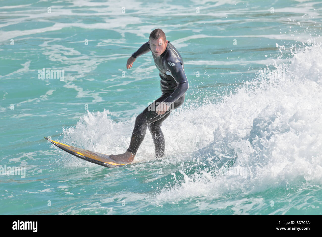 Surfer fängt eine Welle für eine Fahrt ins Ufer am späten Nachmittag Stockfoto