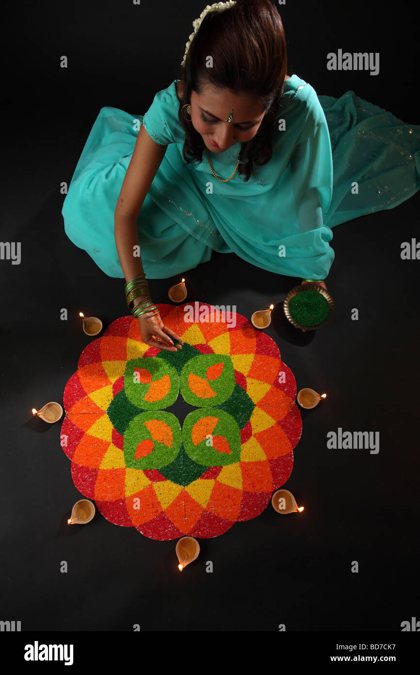 erhöhte Ansicht einer jungen Frau, die Verzierung Rangoli mit Öllampen Stockfoto