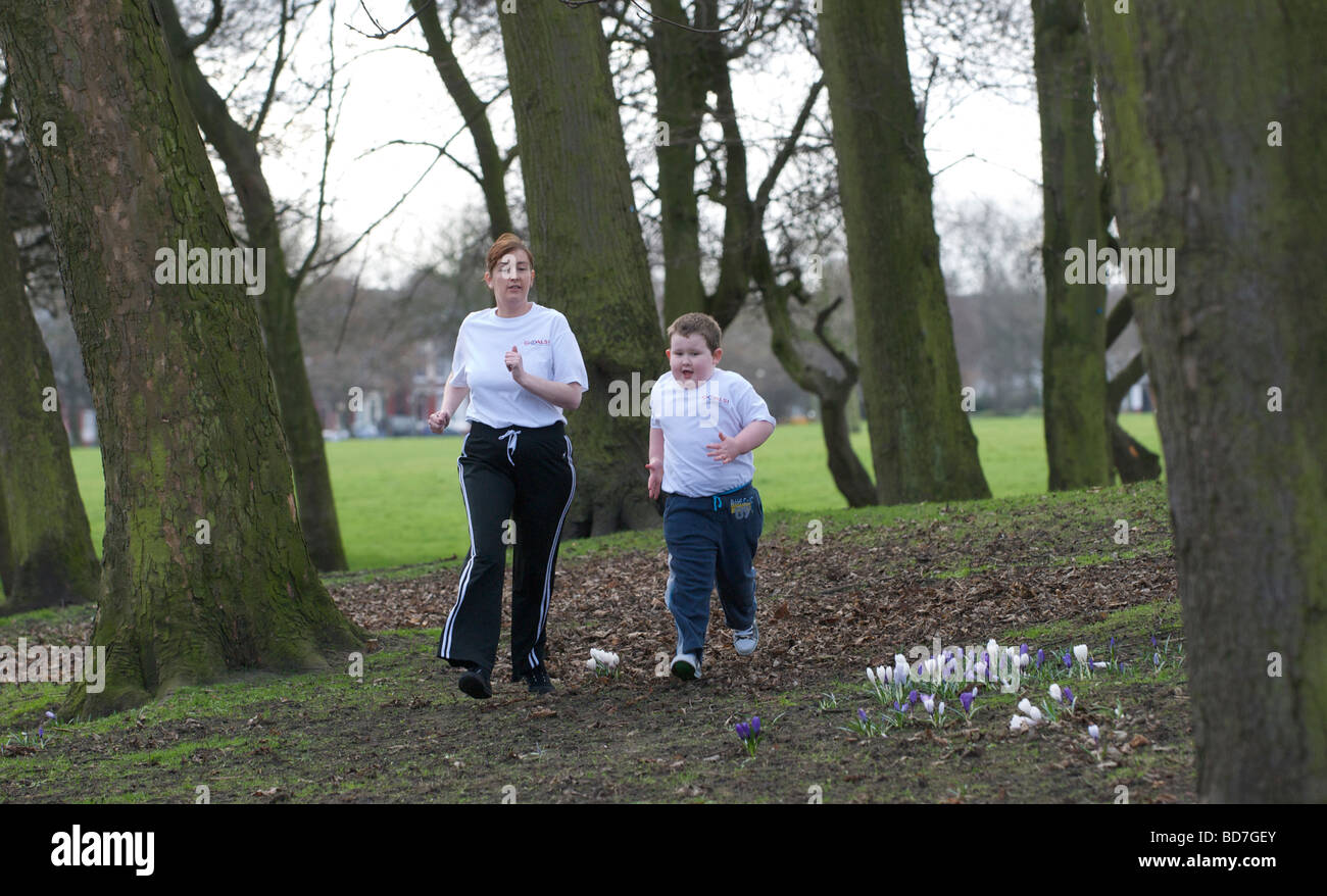 Mutter und übergewichtige Kind auf einen gesunden Lebensstil-Programm "Ziele" spazieren fahren in einem Park in Liverpool. Stockfoto