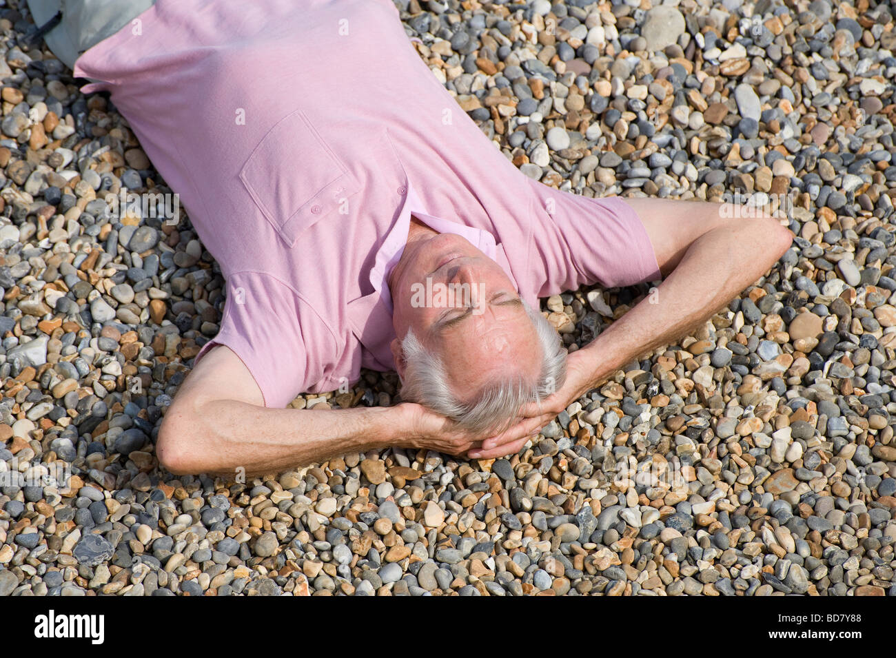 Übersicht über den erwachsenen Mann, der am Kiesstrand liegt Stockfoto