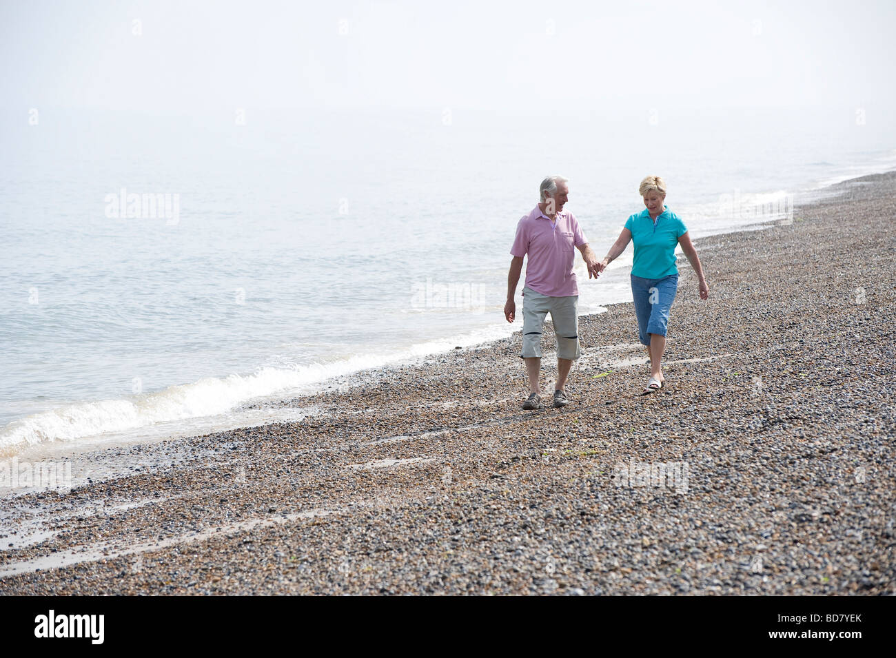 Älteres Paar zu Fuß am Kiesstrand Stockfoto