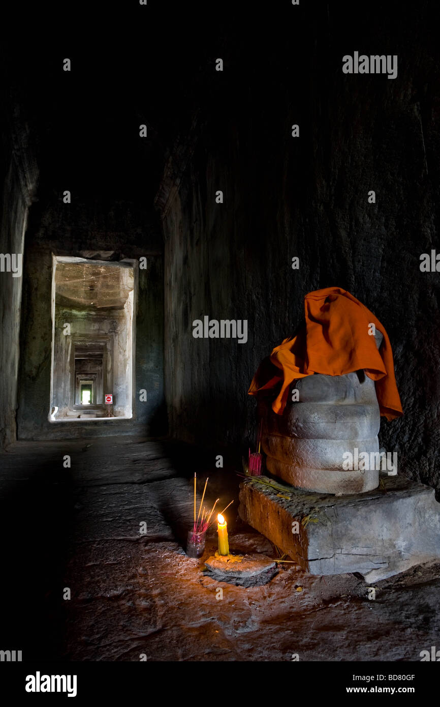 Eine Buddha-Statue in einen Korridor von Angkor Wat mit Weihrauch und eine Kerze brennen Stockfoto
